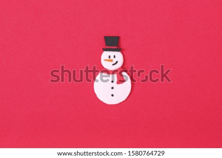 a handmade clay sculpture snowman wearing a red scarf and top hat on the red background