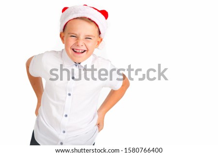 Cute caucasian boy with Christmas red hat and white shirt thinks about something. Picture from the white studio.