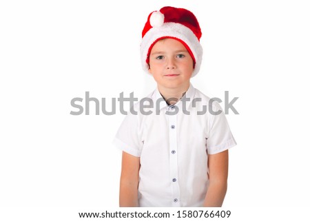 Cute caucasian boy with Christmas red hat and white shirt thinks about something. Picture from the white studio.