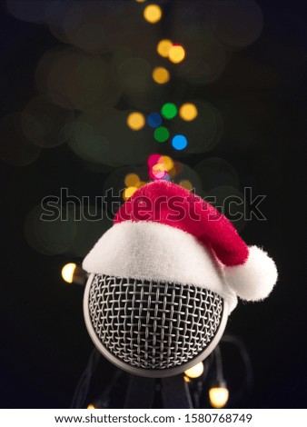 Close up of a microphone with the hat of Santa on a dark studio background, music or recording Christmas concept