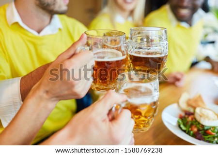 Hands hold beer glass while toasting in a bar or restaurant Royalty-Free Stock Photo #1580769238