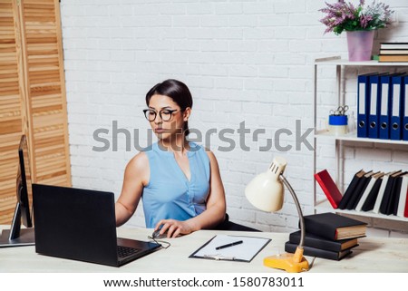 business girl sits in an Office behind a desk with a computer