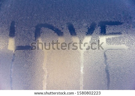 inscription love in the symbol of the heart written on the misted glass with a ribbed and colored structure
