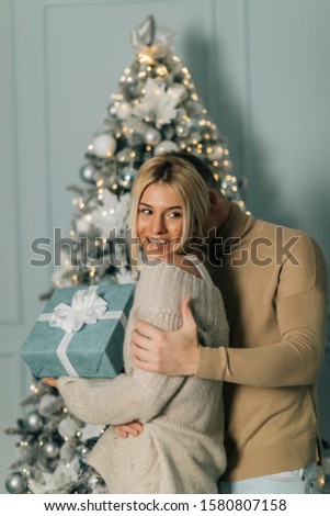 picture of romantic couple in a sweaters with gift box. Boy give a Christmas gift to her girlfriend. Happy young couple background. Magic card.