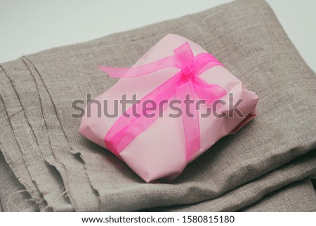 Soft pouch wrapped in craft paper and tie pink silk ribbon. Crumpled paper background texture. Delivery service. Online shopping.	
