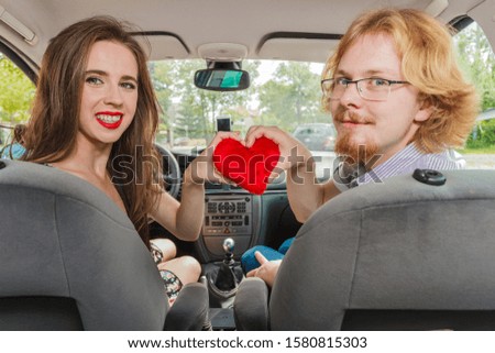 Man and woman having romance in car. Female received heart shaped pillow gift from her boyfriend. Relationship, valentines day concept.