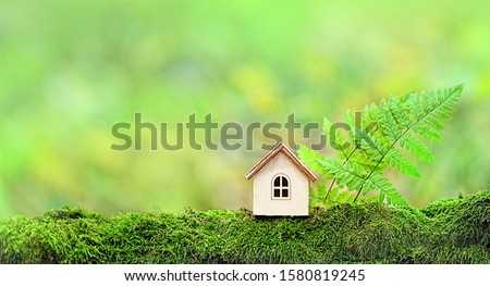 Wooden house and forest leaves on green natural background. Symbol of family, Mortgage, Real estate concept. Eco Friendly House. copy space. template for design