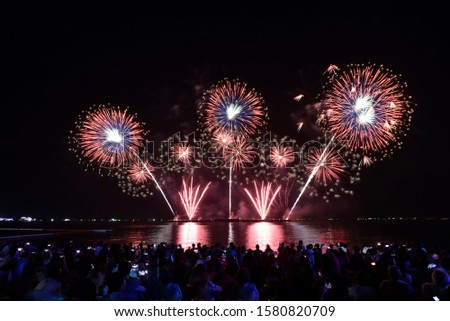 Colorful multiple firework ball (and its reflection) over crowd people on a beach, Pattaya, Thailand