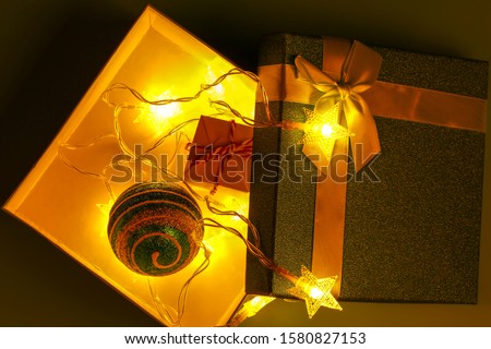 Christmas very dark background. Glowing Christmas garlands. Gift box.