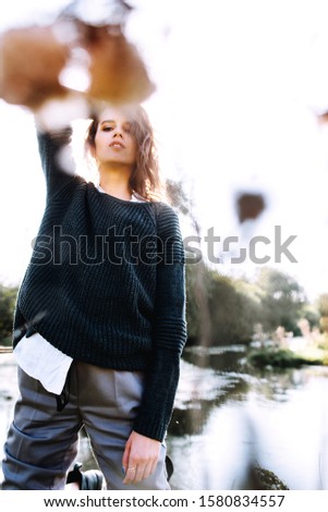 Gentle portrait of beautiful girl or woman in sweater in backlight on river background