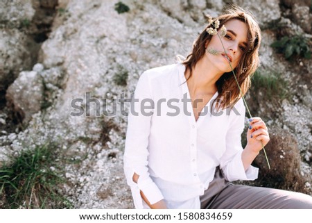 Gentle portrait of a beautiful girl or woman in a white blouse in the backlight on a sandy background