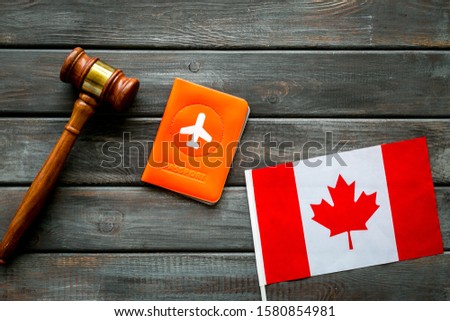 Visa to Canada concept. Canadian flag near passport and judge hammer on dark wooden background top view copy space