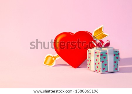 Colorful gift box with red ribbon and red heart-shaped on pink background. Minimal concept for christmas holidays, birthday, valentine, shopping and sales.
