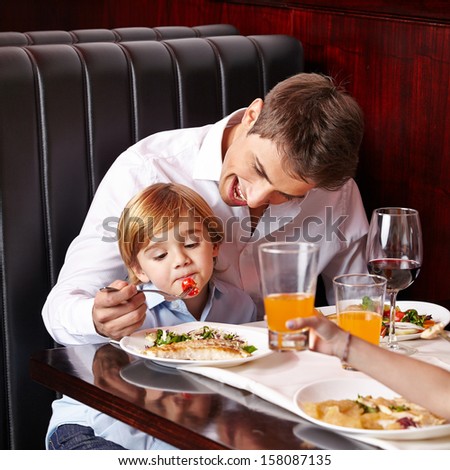 Child is a picky eater in restaurant and father tries to feed it Royalty-Free Stock Photo #158087135