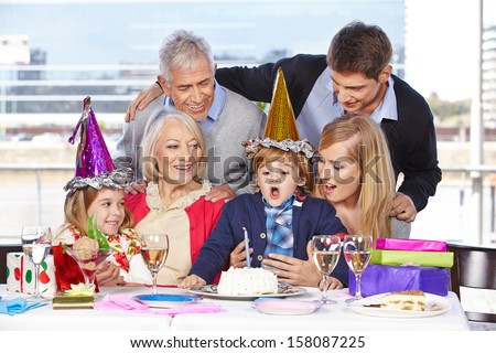 Happy boy blowing out a candle at his birthday party