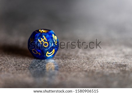 Blue Astrology Dice with symbol of the planet Uranus on grey background