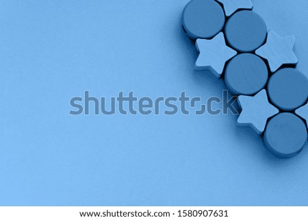 Top view on kids toys on blue paper background. Wooden stars circles in right above corner. Copy space for text, close up. Trendy color of the year 2020.