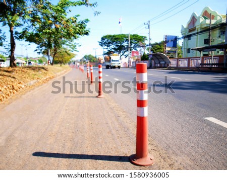 Orange plastic traffic poles on the road - Closeup For traffic barrier for safety On the background of paved roads and buildings blurred.