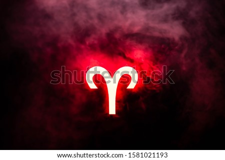 red illuminated Aries zodiac sign with smoke on background