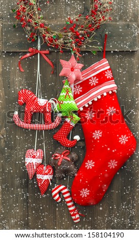 christmas decoration santa's sock and handmade toys over rustic wooden background. nostalgic retro style picture with falling snow effect