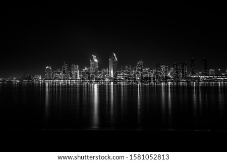 Black and white city view of Downtown San Diego from Coronado Island. City lights at night and reflection on sea. 