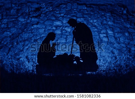 Christmas man nativity scene installation on the theme of the birth of Jesus Christ, shadow and silhouette. Street decoration on eve of Xmas. Toned image with trend color of 2020 year Classic blue