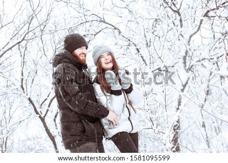 Happy winter holidays. Romantic young couple. Snowy winter day. Christmas and holidays concept - happy couple having fun over winter forest background