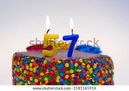 Number fifty-seven candle lit on top of a chocolate confetti cake