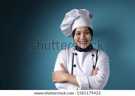 Portrait of happy confident succesful Asian woman chef looking at camera and smiling with crossed arms, against blue background Royalty-Free Stock Photo #1581179422