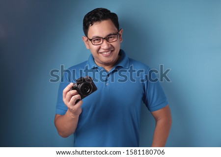 Portrait of funny young Asian man taking picture, shoot with his camera, casual photographer in action