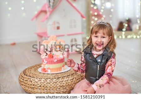birthday cake for 3 years decorated with butterflies, gingerbread kitten with icing and the number three. meringue pale pink in the shape of a rose or flower. the girl is happy holiday she is happy