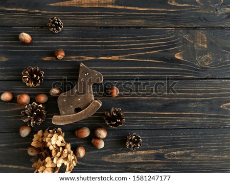 Rustic decorations on wood background. Hand made childish wooden horse, acorns and cones. Space for your text. Christmas greeting card template. Horizontal banner photography.