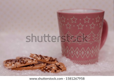 Pink cup of cocoa and chocolate in the snow. Close-up, shallow depth of field. Place for text