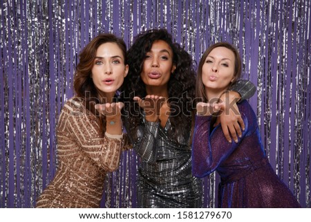 Beautiful cheerful women in fancy sparkling dresses posing isolated over vibrant purple violet silver background. Positive people spending time on happy birthday new year holiday party discotheque