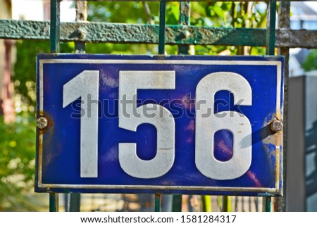 A house number plaque, showing the number hundred fifty six (156)