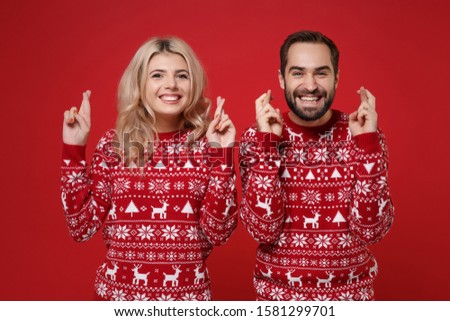 Merry young couple guy girl in Christmas knitted sweaters posing together isolated on bright red background studio portrait. Happy New Year 2020 celebration holiday party concept. Mock up copy space