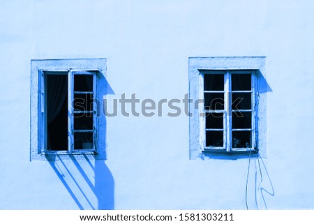 Two vintage windows on a white wall. Image is tinted in color Classic blue. Trend color 2020