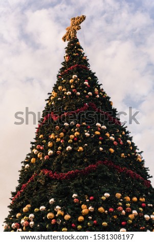 Toned photo of 60 foot Christmas tree with snowflake top, ornament balls and efficient LED lights display at sunset. Typical Xmas decoration at upscale shopping center in Texas, America