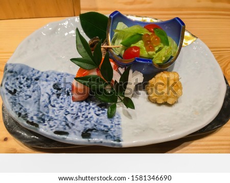A picture of well-decorated and delicious omakase or Japanese chef special sushi which is a high-class oriental cuisine containing shrimp, mixed salad, and seafood in the porcelain plate