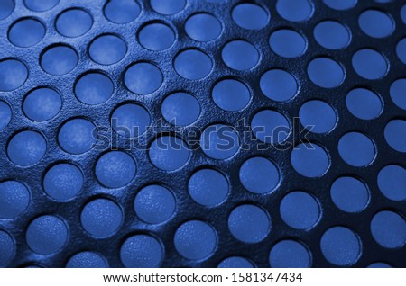 Black metal computer case panel mesh with holes on phantom classic blue color background. Abstract close up image