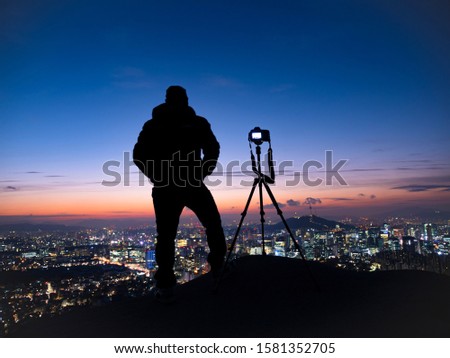 Shadow Man Standing Silhouette on background of Sunrise Sky and Photographer with a camera on tripod in Seoul South Korea  