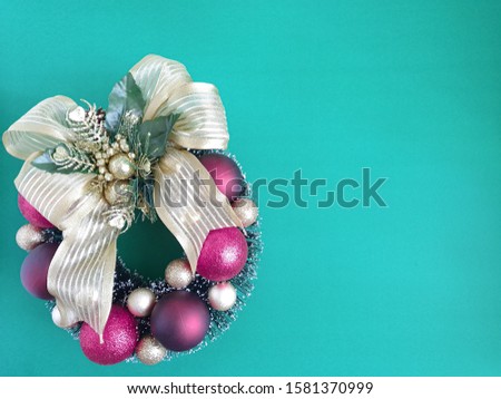 Christmas background in turquoise with decorated garland located on the left side. Free space for message.