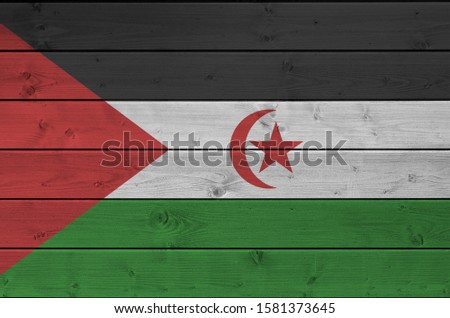 Western Sahara flag depicted in bright paint colors on old wooden wall. Textured banner on rough background