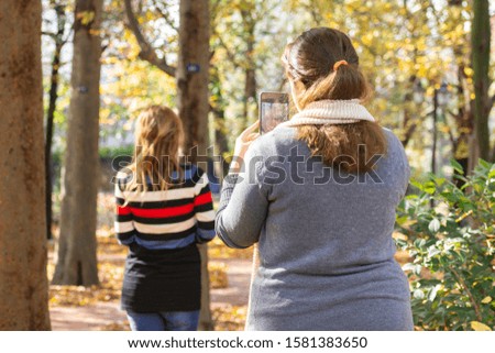 Rear view of a young woman taking picture with smartphone from young woman model in outdoor area