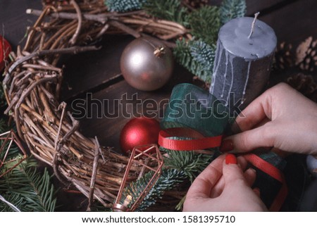 Close-up of a female florist making a Christmas wreath of fir branches, Christmas bubbles and natural decor, selective focus