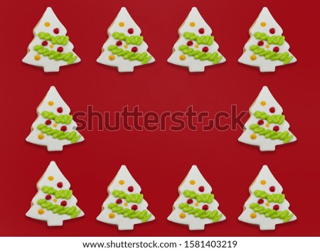 Background of glazed cookies in form of Christmas tree decorated with colorful frosting on red background. with copy space at center point