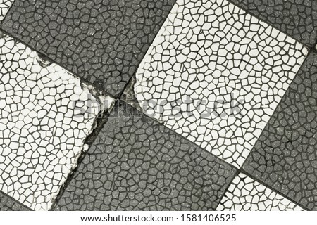 Textured of vintage floor glazed tile in one of the buildings. Old stone tile floor with interesting pattern. Retro floor mosaic with cracks. Cracked and weathered stone slab. Ancient ceramic tile.