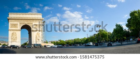 Panorama of The Arc de Triomphe in Paris, with copyspace. Eiffel Tower in the background with cars parked near the monument on a cloudy bright day