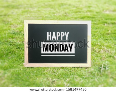 Happy Monday text written on the blackboard with green grass background.