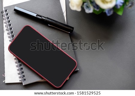 smartphone with black screen on black cover notebook on black leather top table, copy space.